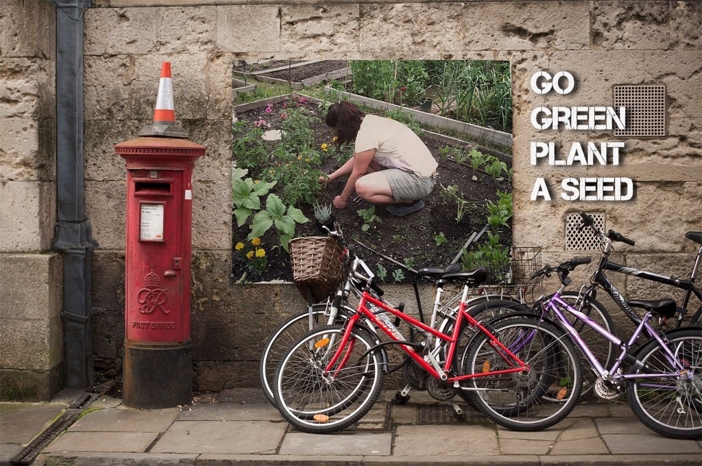 Mehrere Fahrräder sind in der Nähe einer Briefkasten mit einer Sicherheitskegel auf der Spitze geparkt, mit einem Plakat an der Wand im Hintergrund und einem Weg am unteren Rand des Bildes.