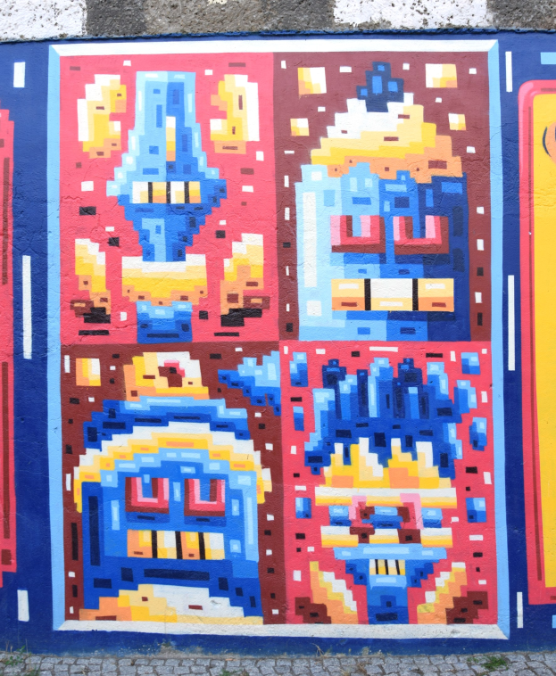 Ein leuchtendes, farbenfrohes Wandgemälde, das die Seite eines Gebäudes in Berlin, Deutschland, bedeckt und verschiedene Formen und Farbtöne zeigt.