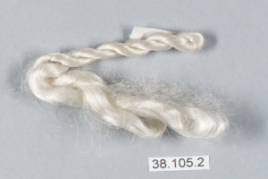 Ein Faden weißer Seide mit einer darauf geschriebenen Zahl auf einer grauen Oberfläche.