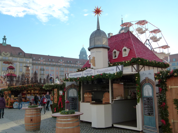 Ein geschäftiges Weihnachtsmarkt in Nürnberg, Deutschland mit Menschen um geschmückte Stände, festliche Lichter, ein Riesenrad, Gebäude und ein Schild im Hintergrund.