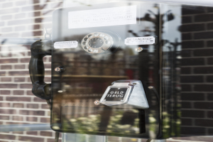 Ein altmodisches Münztelefon steht auf einem Glasfenster, im Hintergrund eine Wand.