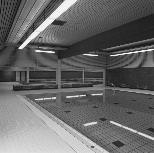 Innenpool mit klarem Wasser, gefliesten Wänden und Boden, Deckenbeleuchtung und minimaler Umgebung in einem großen, ruhigen Raum.