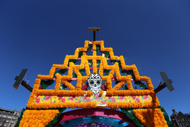 Ein Día de los Muertos-Bogen, geschmückt mit Blumen und einem Schädel, vor einem Gebäude und einem klaren blauen Himmel in Mexiko-Stadt.