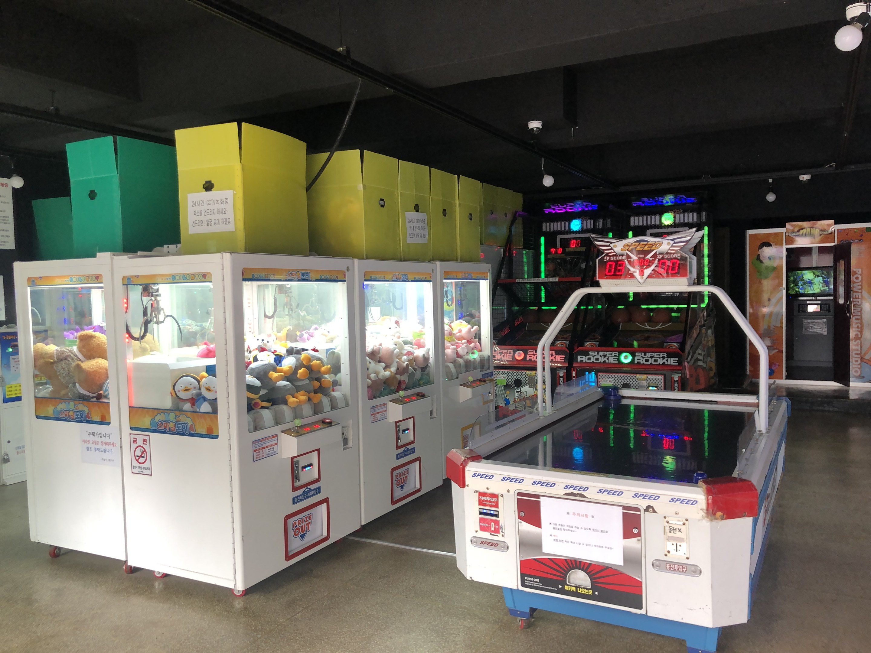 Ein vollgestopfter Arcade-Raum mit verschiedenen Arcade-Spielen, einer beleuchteten Decke und einem sichtbaren Boden.