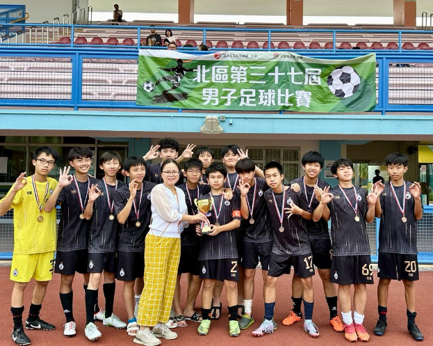 Gruppe junger Männer in Fußballuniformen auf einem Feld mit einem Pokal und einem Banner 'Yokohama U-16 Boys Soccer Team' im Hintergrund.