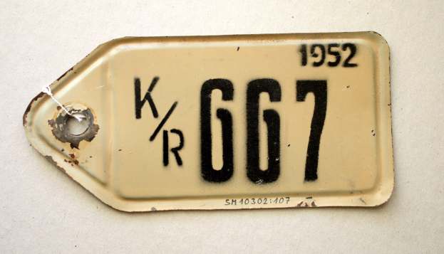 Weiße Fläche mit einer angebrachten Nummernschild, das alphanumerische Texte und Zahlen anzeigt.