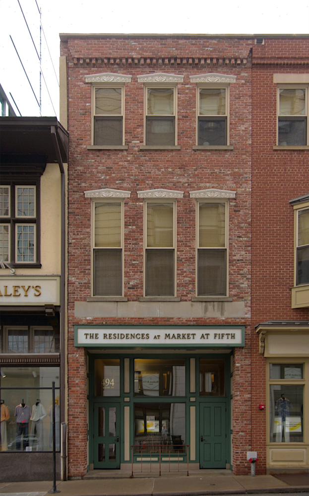 Ladenfront von "Residences at Market at Fifth" mit Glasfenstern und -türen, Schaufensterpuppen in Kleidern, einer Straße darunter und Himmel im Hintergrund.