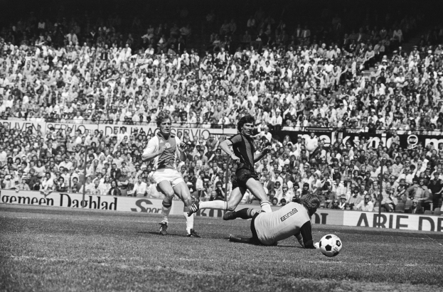Schwarz-weißes Foto von Männern, die auf einem Feld Fussball spielen, mit Zuschauern im Hintergrund und einem Banner mit der Aufschrift "Bundesliga 1978-79 Ajax 1-1 Hannover 96".