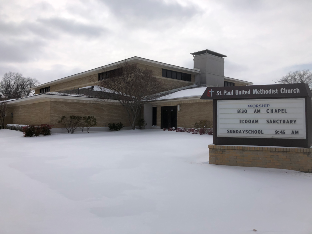 St. Paul United Methodist Church, ein Gebäude mit Fenstern und Türen, umgeben von Pflanzen und Bäumen, mit Schnee auf dem Boden und einem bewölkten Himmel im Hintergrund, mit einer Tafel mit Text darauf auf der rechten Seite.