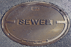 Metallschachtdurchlass auf der Straße mit der geprägten Aufschrift "Kanal"