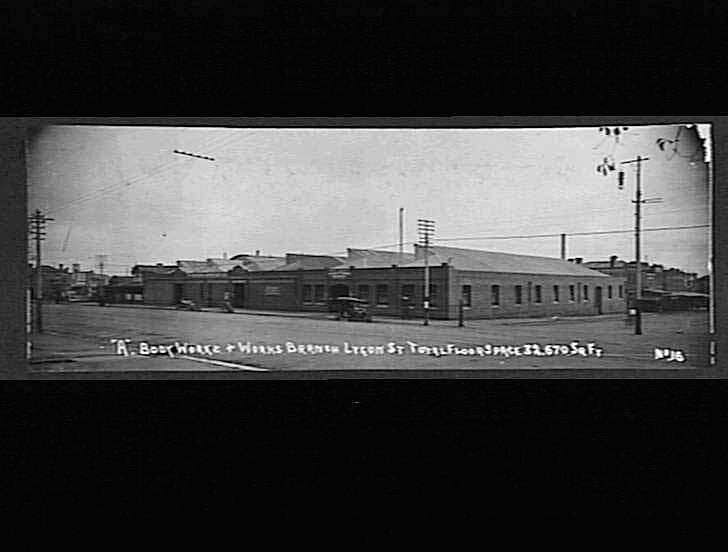 Schwarzes und weißes Foto einer Stadtstraße mit Gebäuden, Strommasten, Kabeln, Fahrzeugen und einem Himmel, mit Text unten, der 'Book House and Works, Bergen, Oregon' lautet.