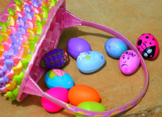 Ein geflochtener Korb und mehrere bunte Ostereier an einer Wand.