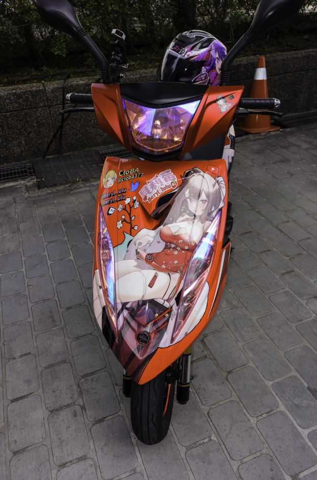 Ein oranges E-Scooter auf dem Straßenrand mit einem Helm darauf, mit einem Verkehrskegel, einer Wand und mehreren Bäumen im Hintergrund.