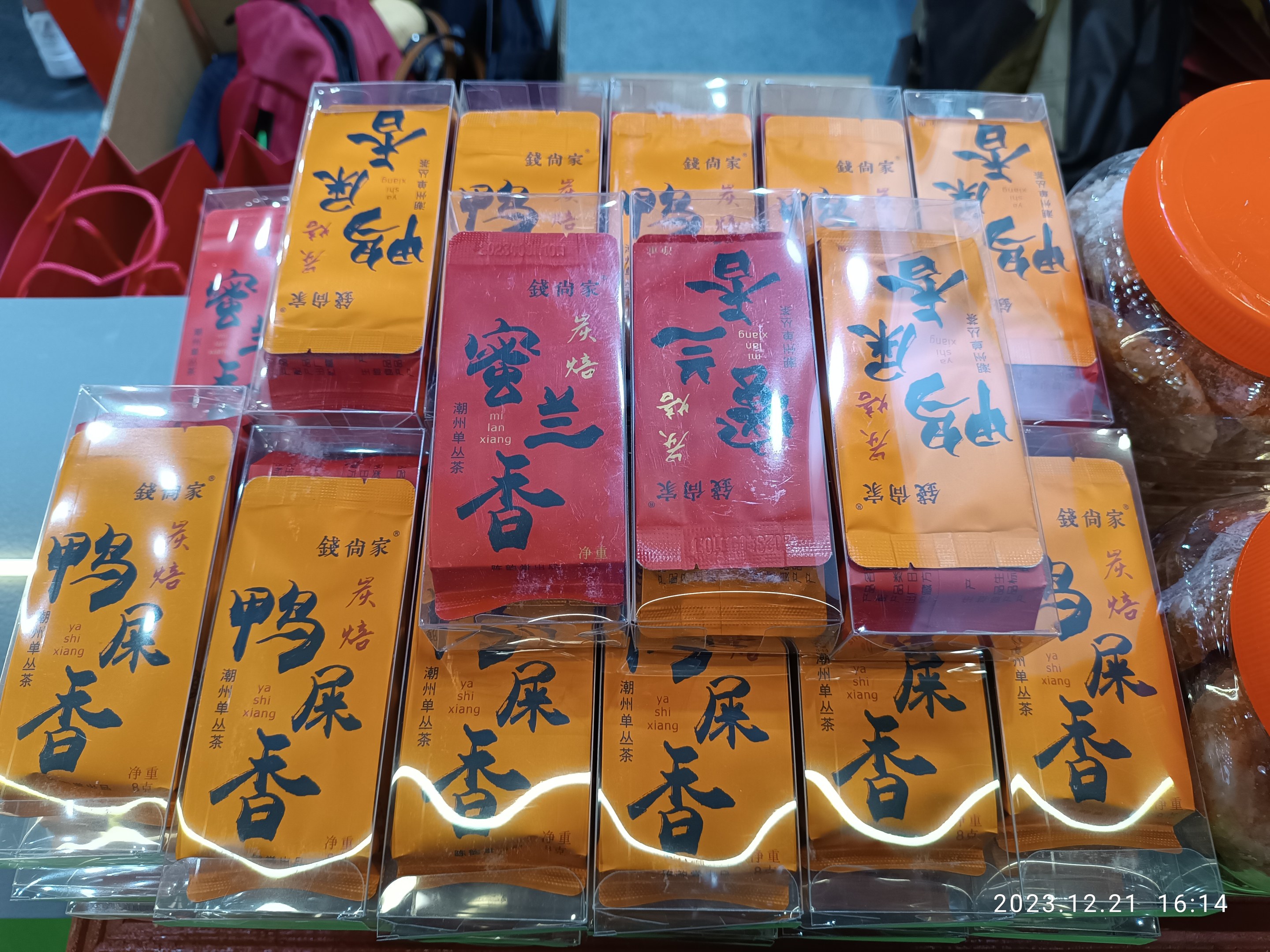 Ein Tisch mit verschiedenen verpackten Lebensmitteln und Gegenständen, im Hintergrund steht eine Person während eines chinesischen Neujahrsfests.