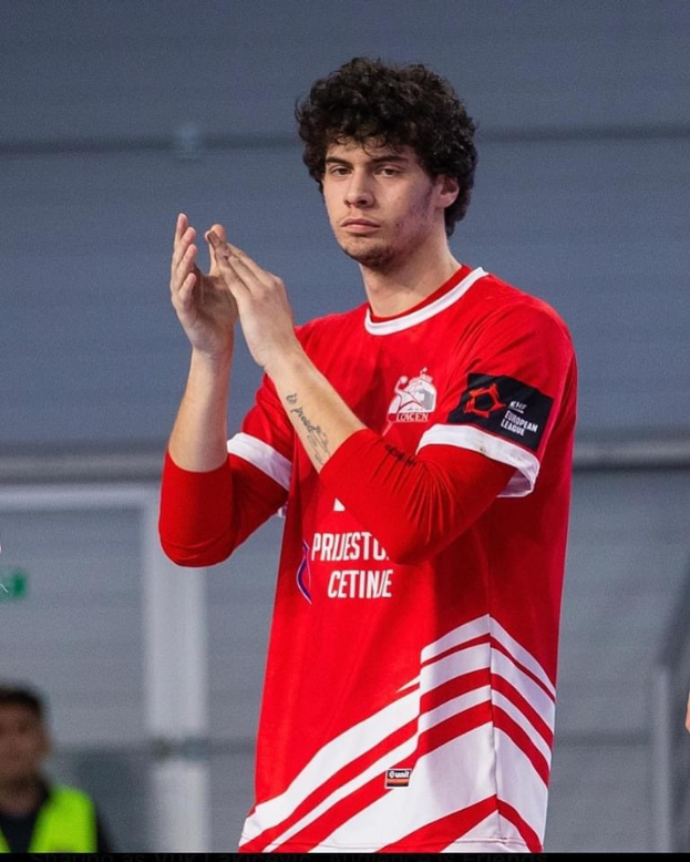 Ein Mann in rot-weißem Shirt klatscht im Vordergrund mit einer anderen Person und einer Wand im Hintergrund, mit Text 'Copenhagen Futsal Club - Foto 1' unten.
