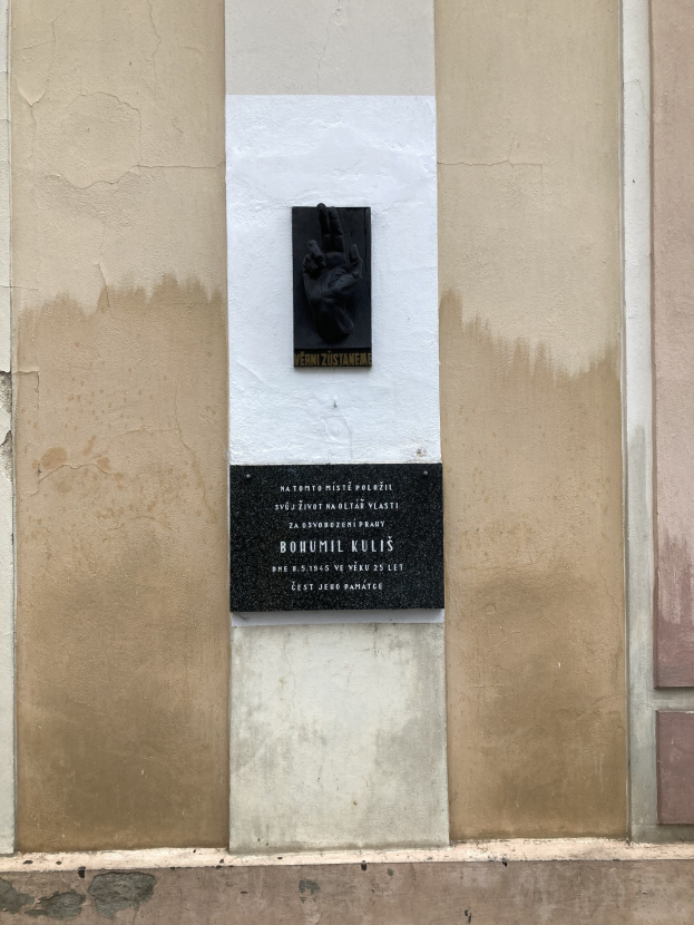 Schwarze Tafel an einem Gebäude mit einer darauf liegenden Hand, die wahrscheinlich Holocaust-Opfer gedenkt.