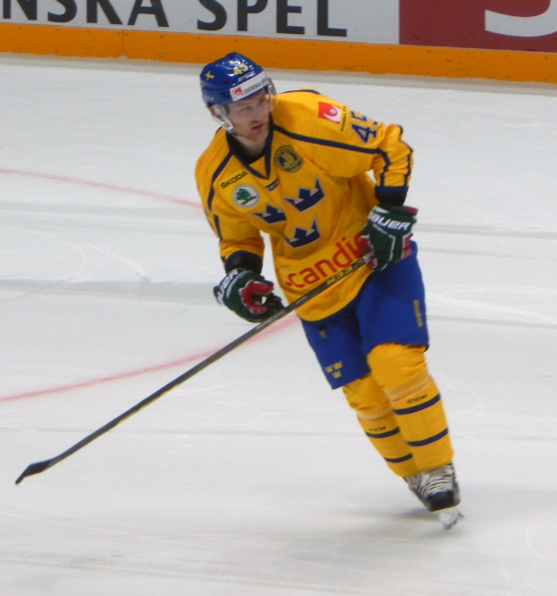 Eishockeyspieler in Bewegung auf dem Eis, trägt Helm, Handschuhe und Schlittschuhe, hält einen Hockeystock und hat ein Textfeld im Hintergrund.