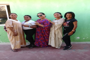 Gruppe von Frauen, die vor einer grünen Wand mit einem Fenster stehen und an einem Internationalen Frauentag teilnehmen.