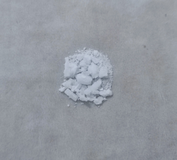 Ein Haufen weißes Salz auf einem Zementboden, mittig vor einem weißen Hintergrund.