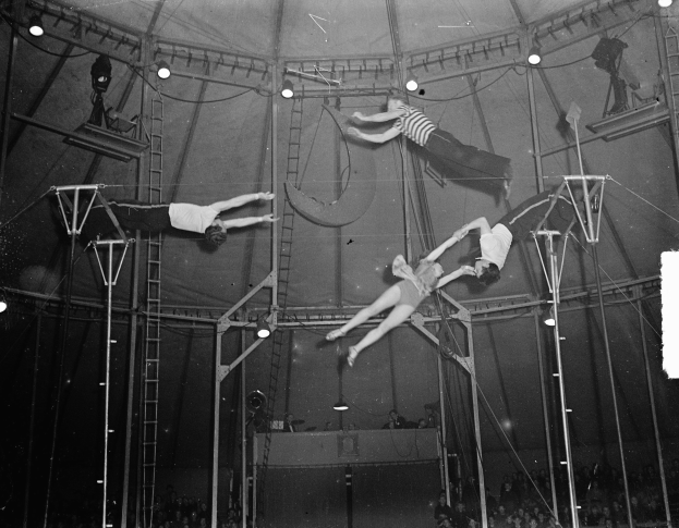 Schwarz-weiß-Foto von Akrobaten, die in einem Zirkuszelt performen