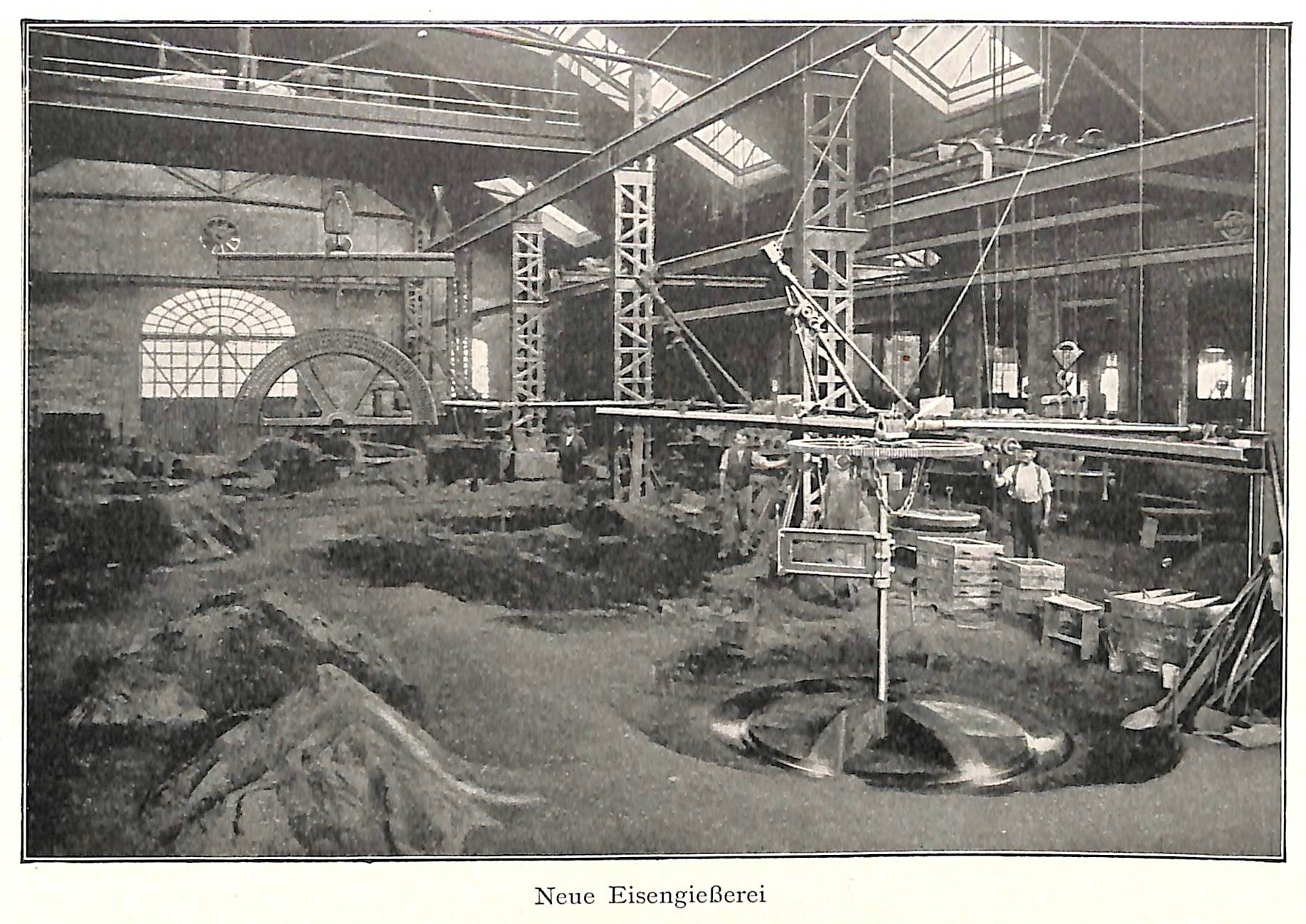 Schwarz-weiß-Fotografie einer Fabrik mit Arbeitern, die an einer Maschine arbeiten, umgeben von Metallstangen und -pfählen, beschriftet mit "Neue Eisengießerei, die erste Fabrik Deutschlands" unten.