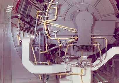 Große industrielle Beschleuniger-Maschine mit mehreren verbundenen Komponenten und Kabeln in einem Gebäude.