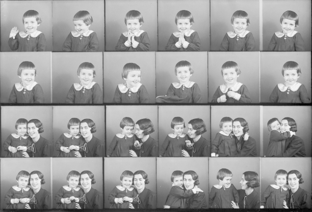 Schwarz-weißes Foto einer Gruppe von Kindern mit einer Frau in der Mitte, die ein Baby hält und beide warm lächeln